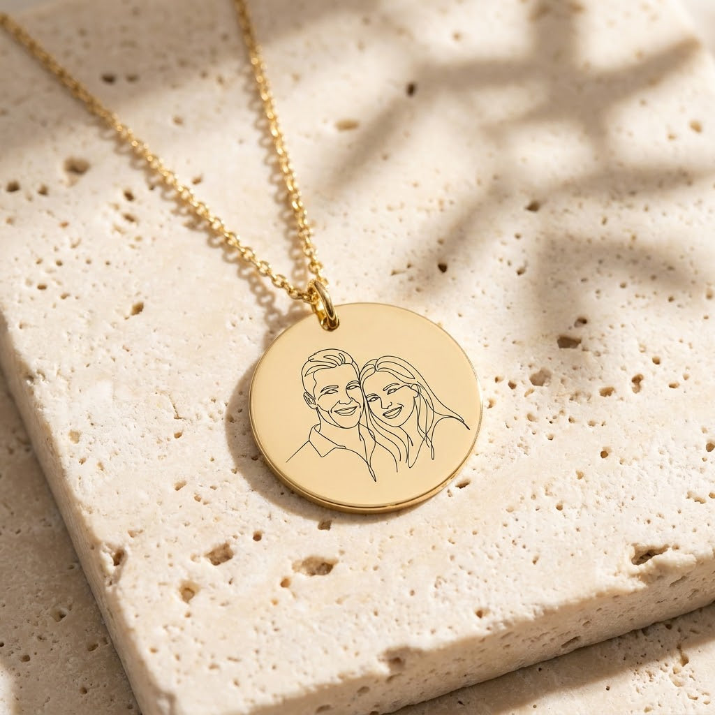 Gold photo necklace engraved with a line-art portrait of a couple
