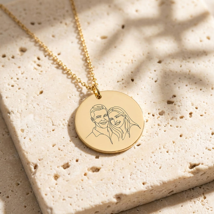 Gold photo necklace engraved with a line-art portrait of a couple